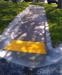 A Sidewalk With Yellow Safety Bar on Path